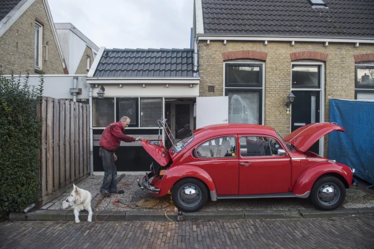 Man bij rode eend (auto) en witte herdershond in de Vlietzone